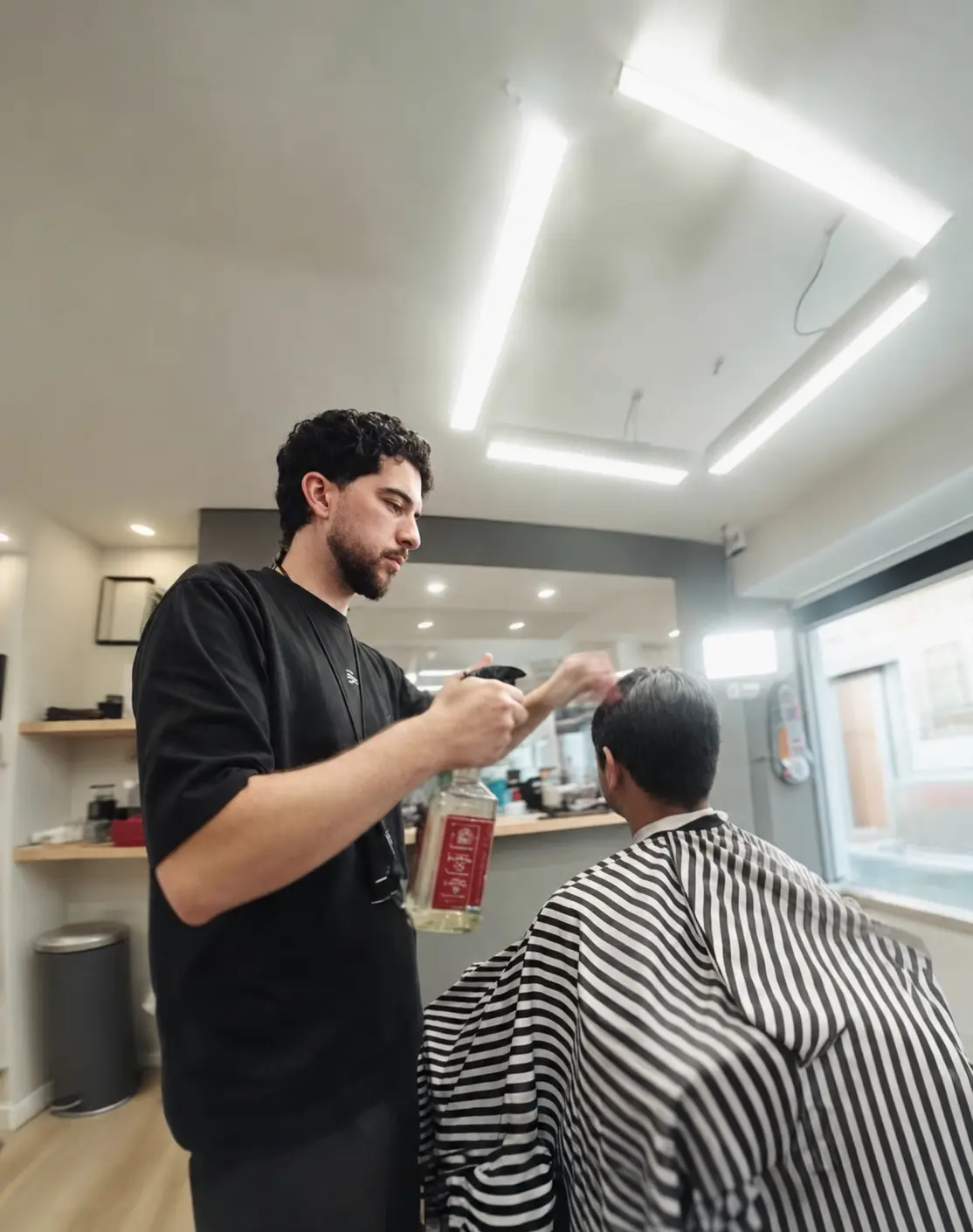 Fred a trabalhar num corte masculino à tesoura na sua barbearia em Leiria